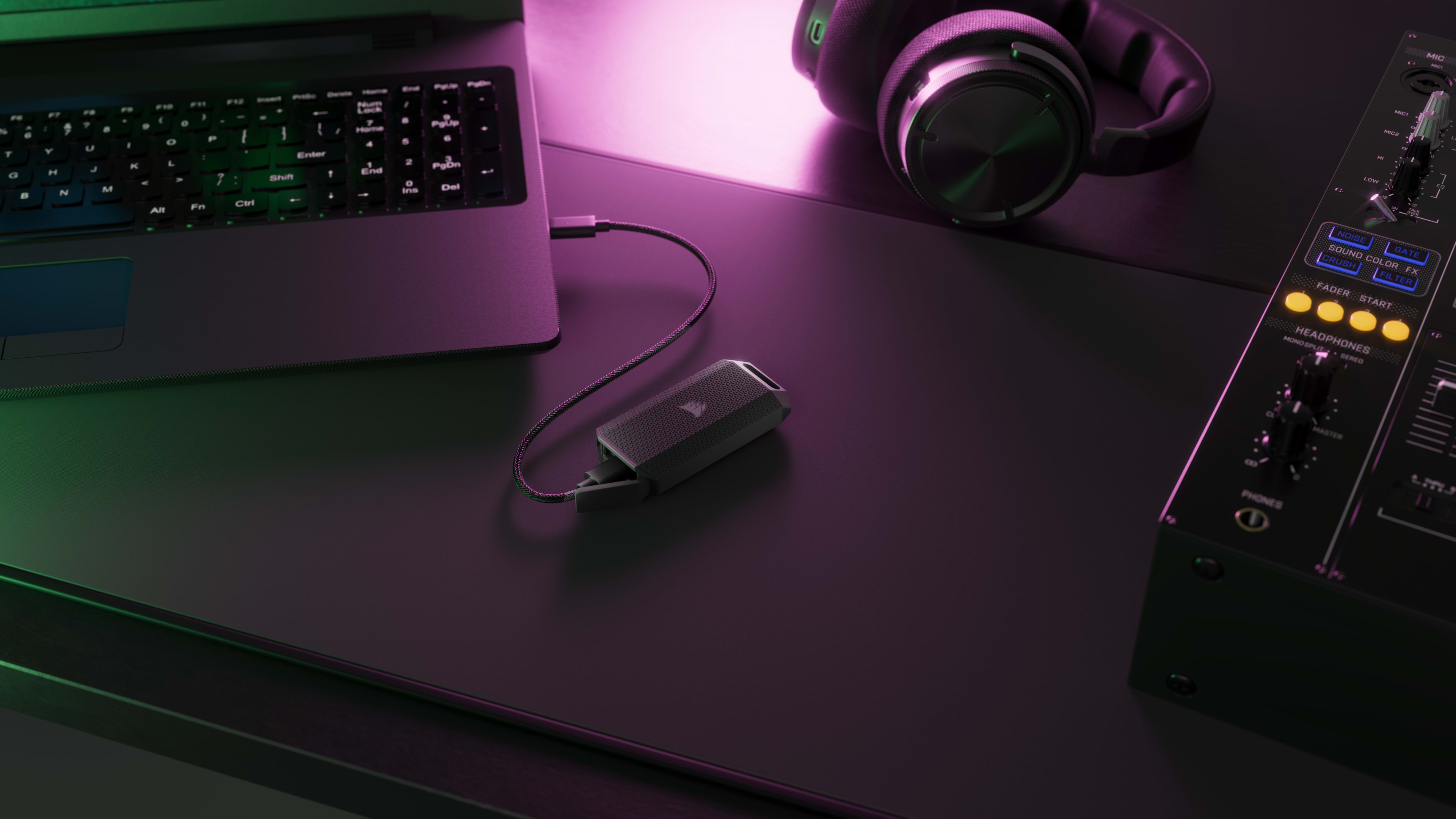 CORSAIR EX400U Survivor portable SSD connected to a laptop on a dark desk with purple RGB lighting and headphones nearby.