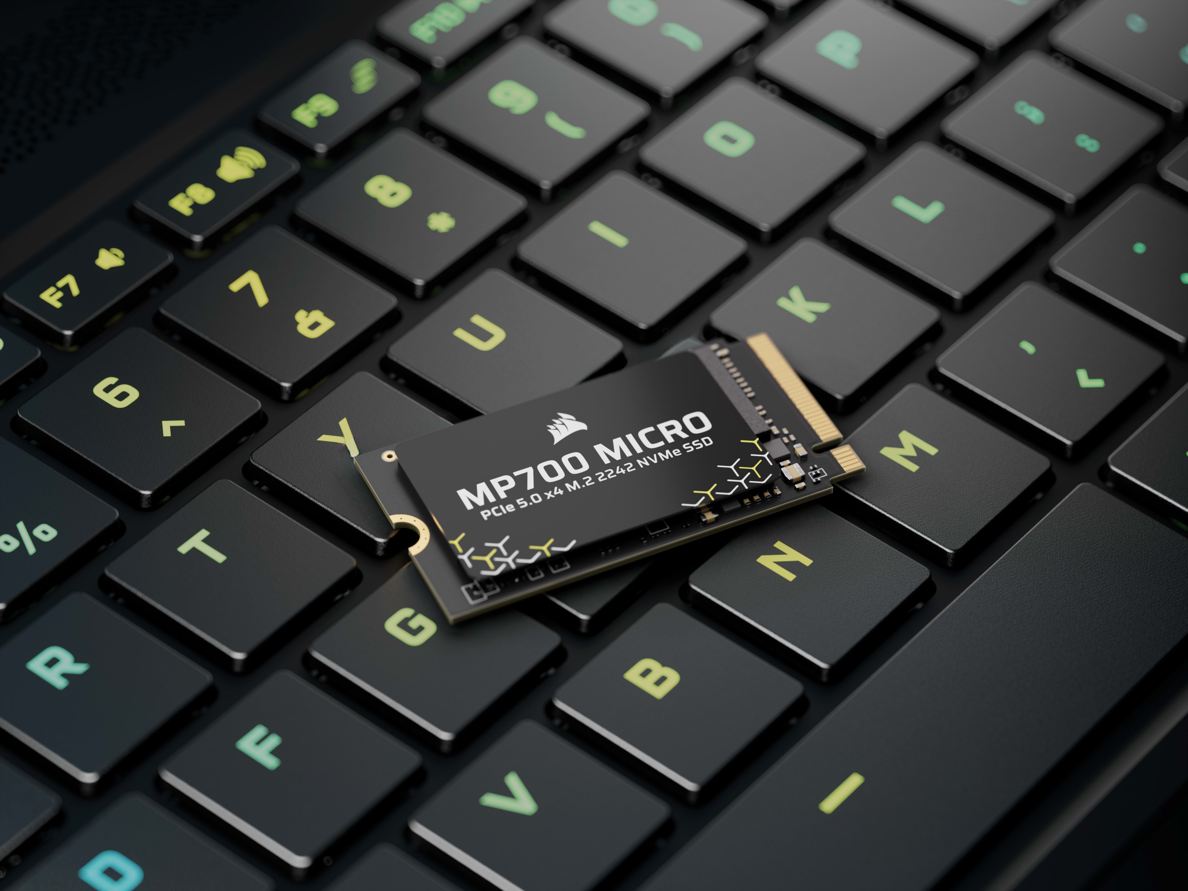 CORSAIR MP700 MICRO M.2 2242 SSD resting on a gaming laptop keyboard with yellow-green RGB backlighting.