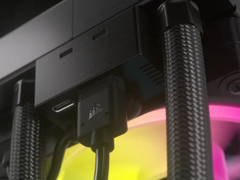 Close-up of a CORSAIR iCUE LINK USB-C connector plugged into a component with RGB liquid cooling tubes in the background.