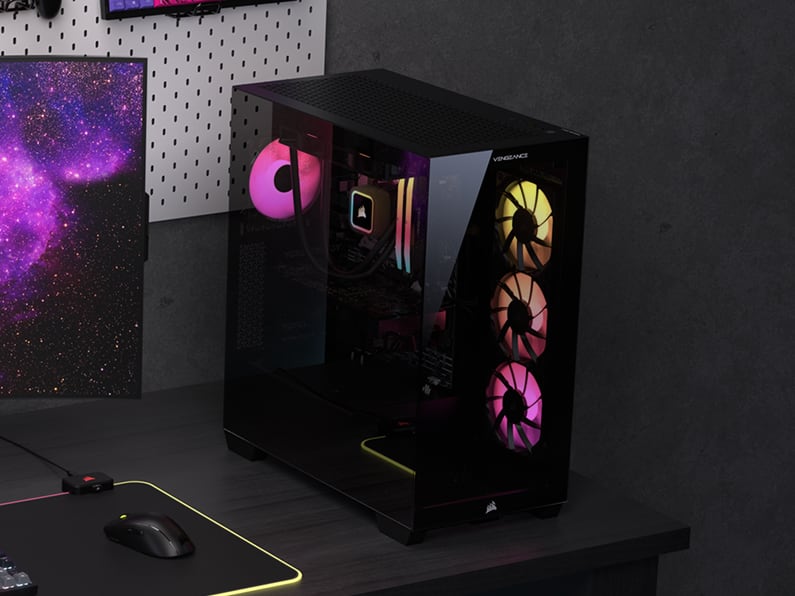CORSAIR VENGEANCE gaming PC tower with tempered glass side panel showing RGB fans and components inside on a gaming desk.