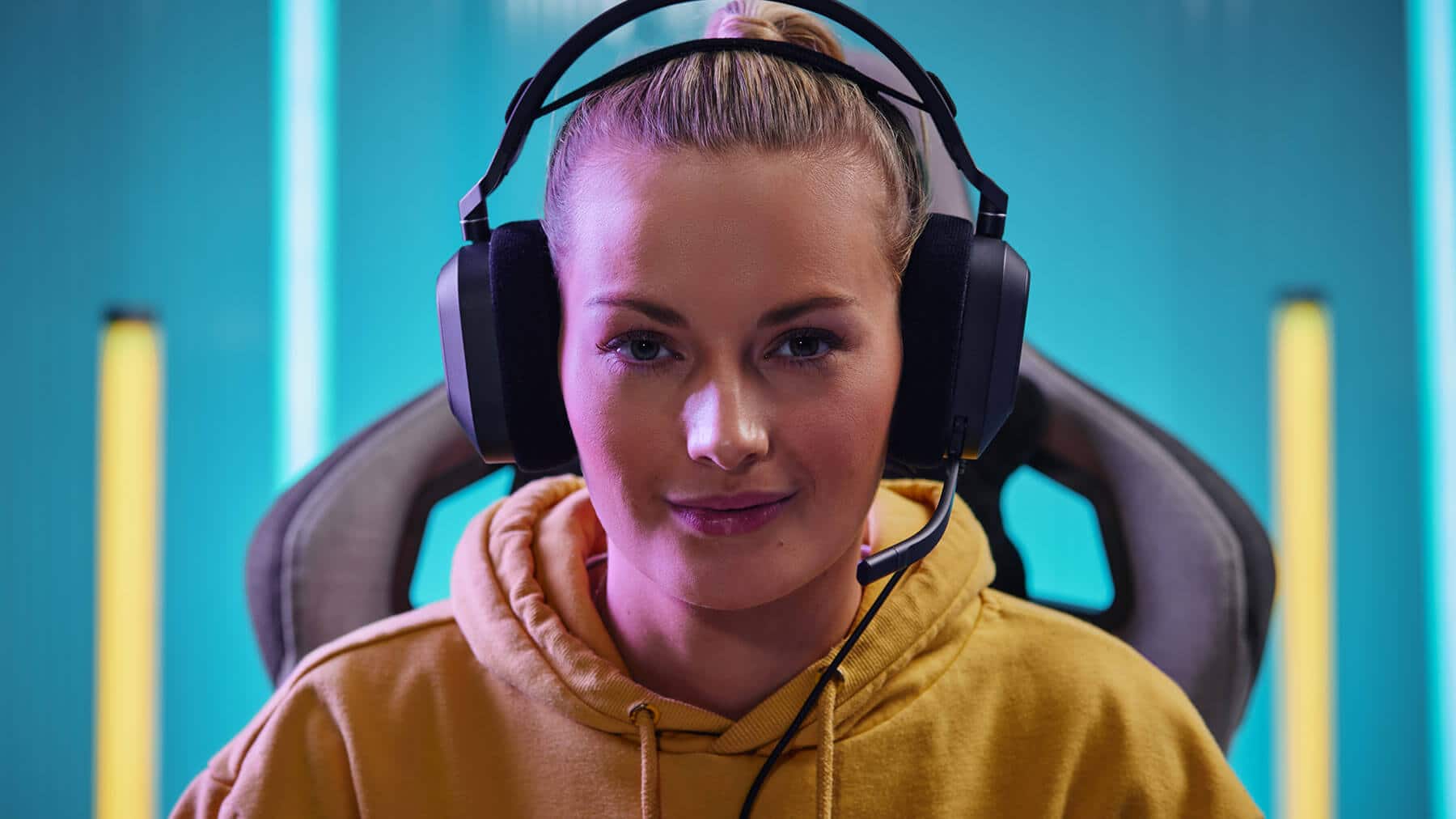 Woman with hair tied back looking directly forward with HS80 RGB USB headset demonstrating the comfortable floating-headband design.