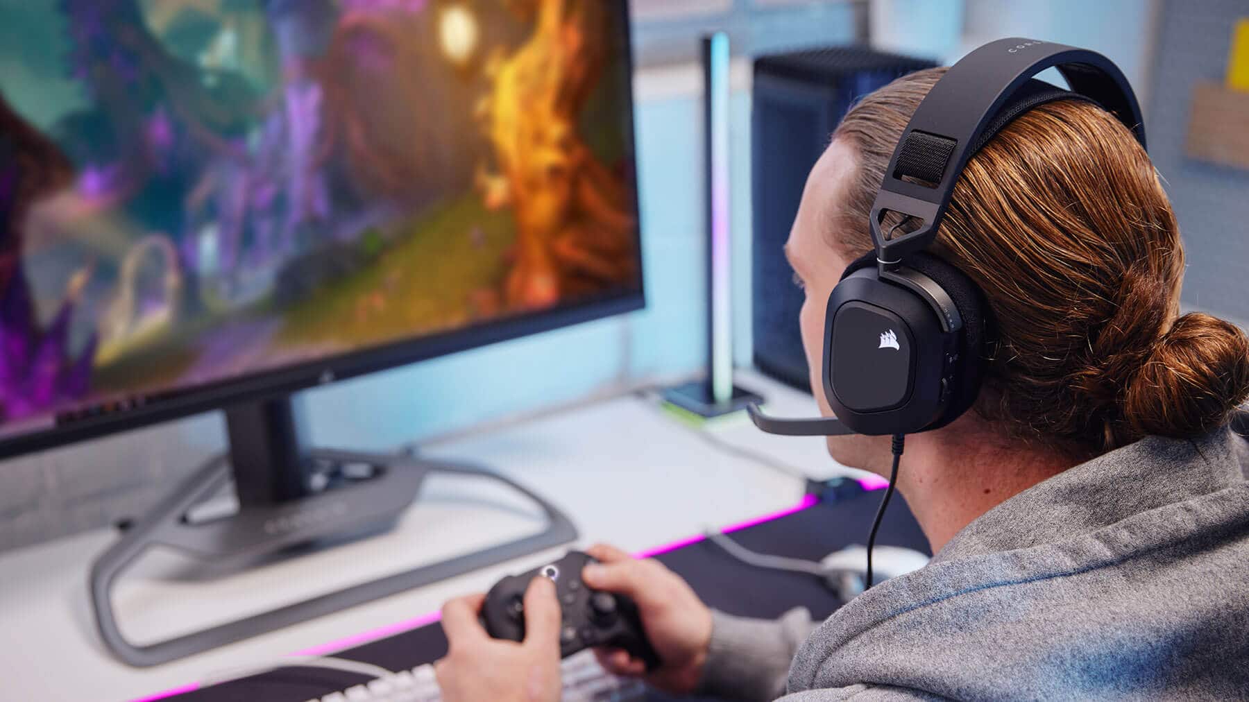 Man playing PC games while using the HS80 RGB USB Gaming Headset.