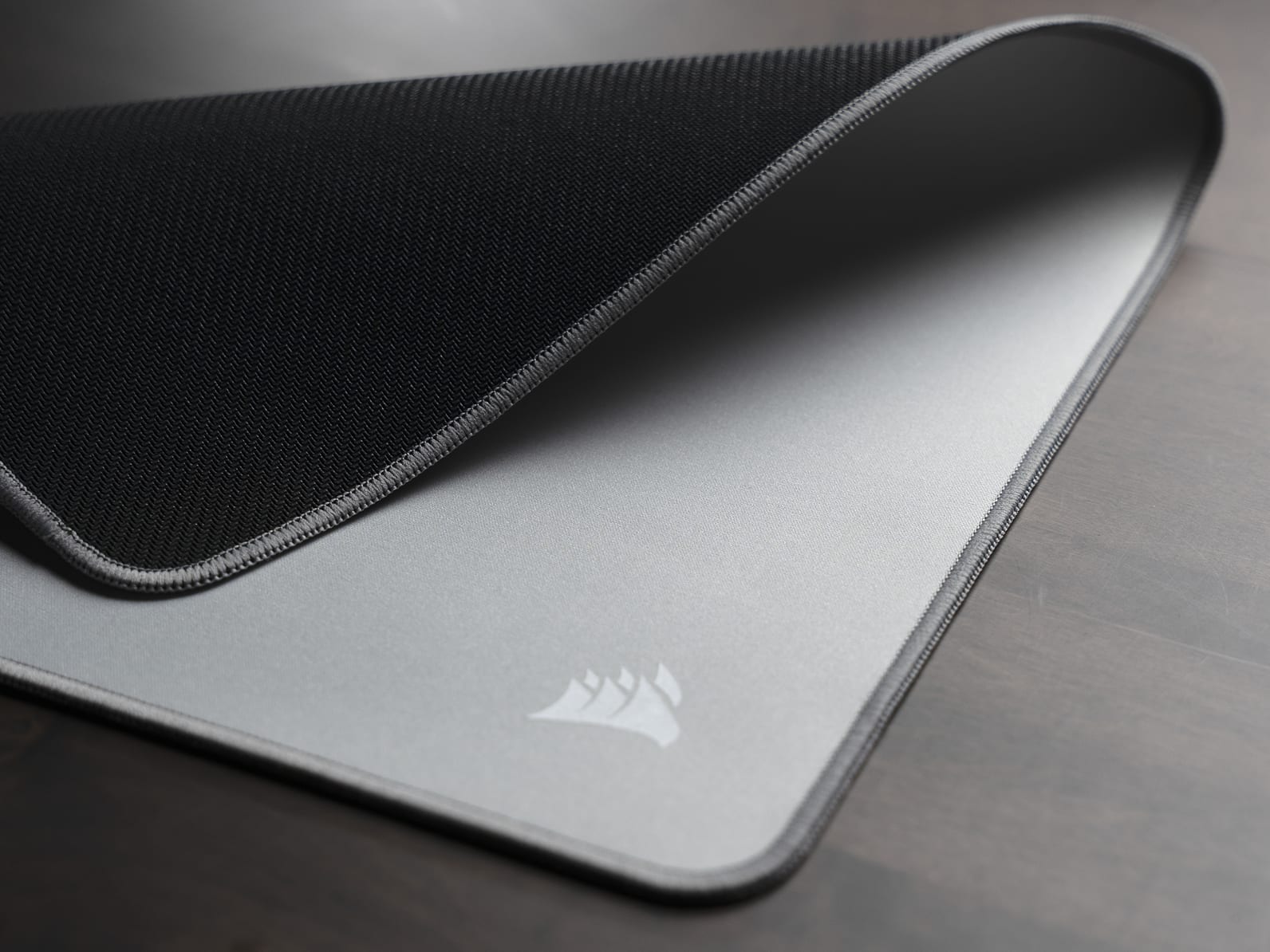 MM CLOTH mousepad corner showing the silver surface and stitched edge, never let victory slip away feature