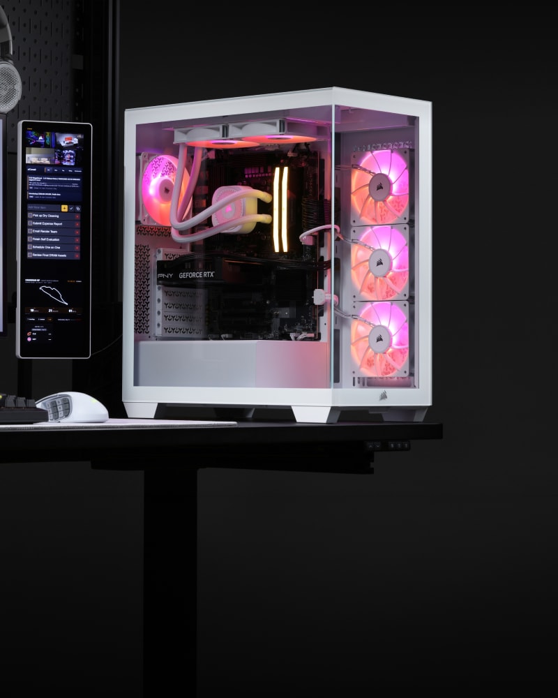 Corsair Vengeance a7500 gaming PC on a home desk with RGB lighting, AIO cooler, and case fans visible through the tempered glass panel.
